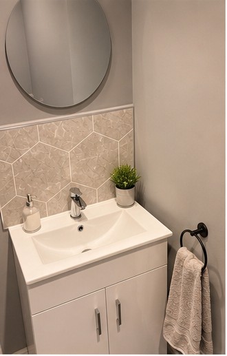 Bathroom with round mirror, basin and tiled splashback