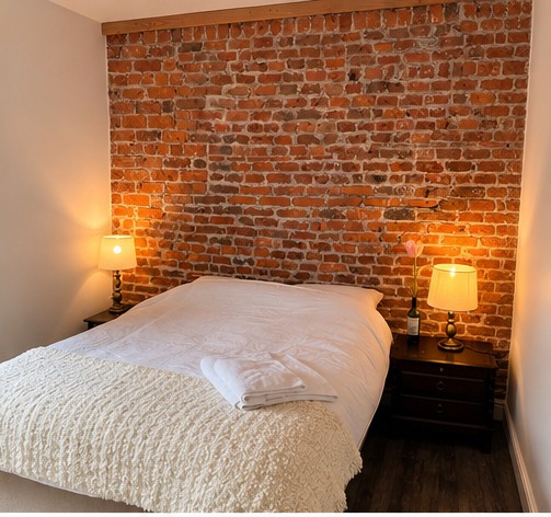 Double bedroom with exposed brick wall and bedside lamps