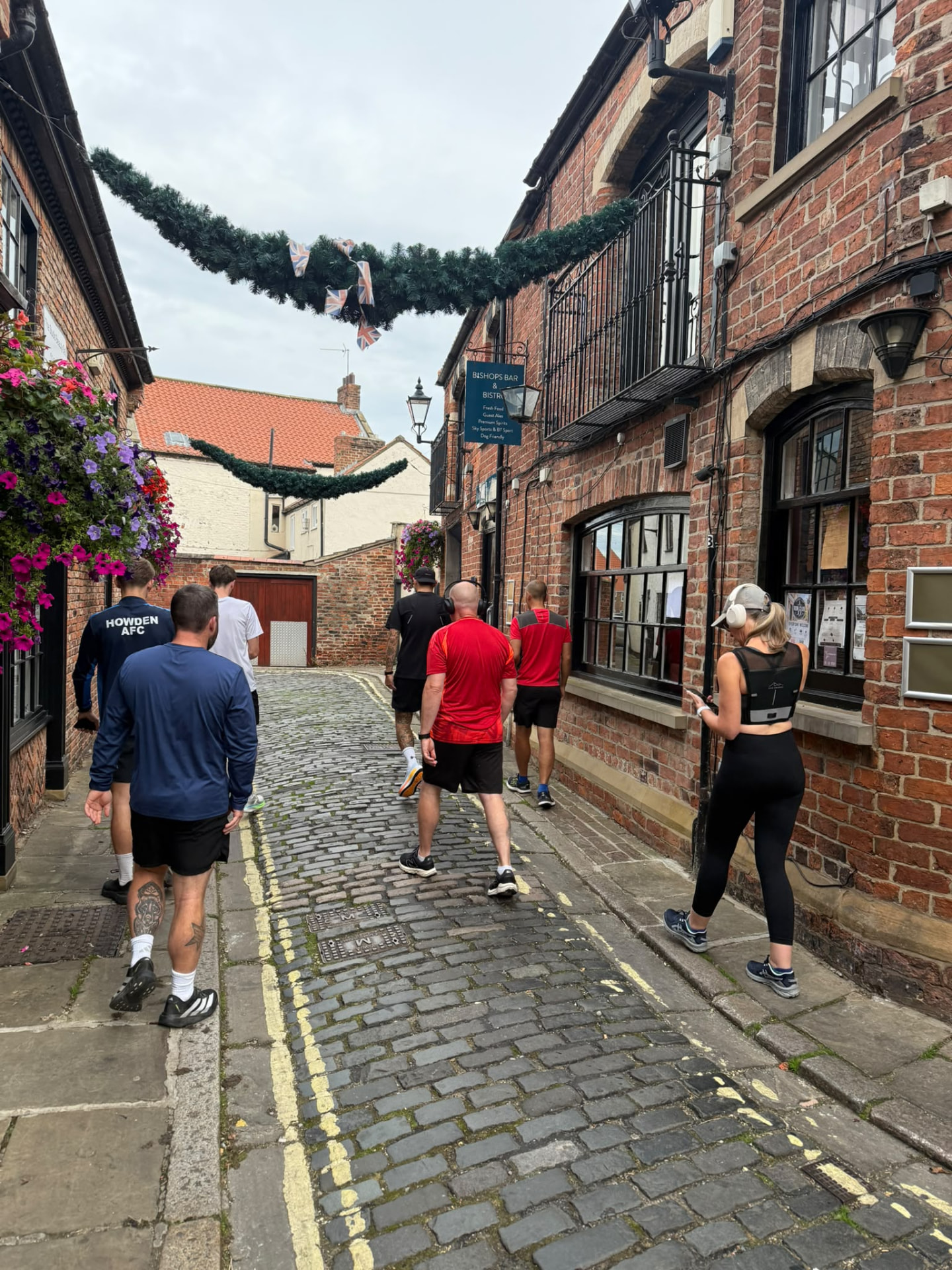 Run club heading down the cobbles past the Bishops sign